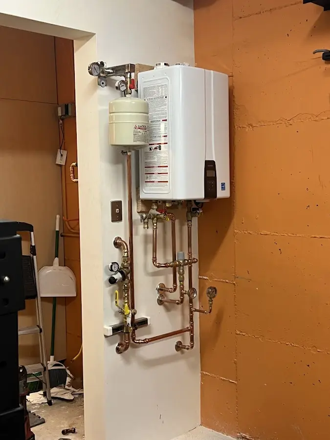 Plumbing technician inspecting water heater connections in Flower Hill